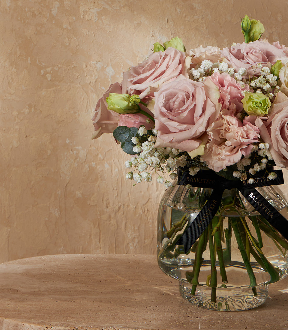 Elegant nude and white rose vase arrangement with fresh flowers in clear ribbed glass