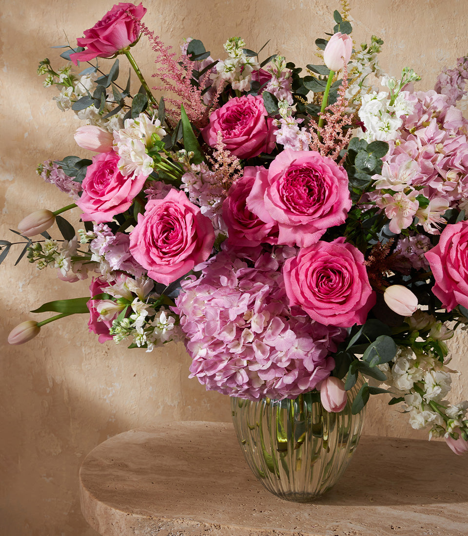 Pink rose and hydrangea vase arrangement with eucalyptus and white stock flowers in ribbed glass