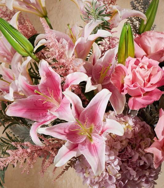 Blush pink floral arrangement with stargazer lilies, roses, hydrangeas, and astilbe in premium vase