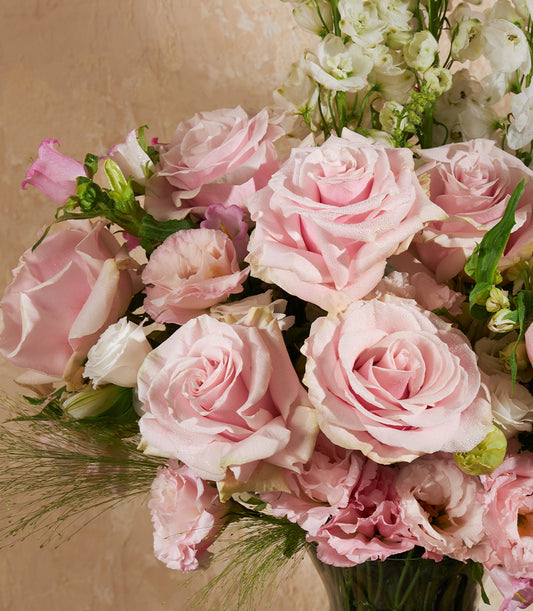 Fresh pink roses and white eustoma arrangement in glass vase with dewy petals