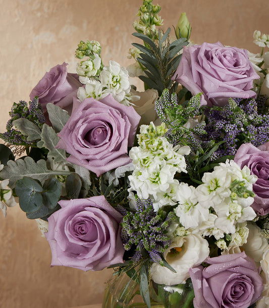 Lavender roses with white stock and eucalyptus in fresh glass vase arrangement