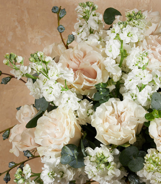 Ivory Whisper white and blush rose vase arrangement with eucalyptus and blue-green berry accents