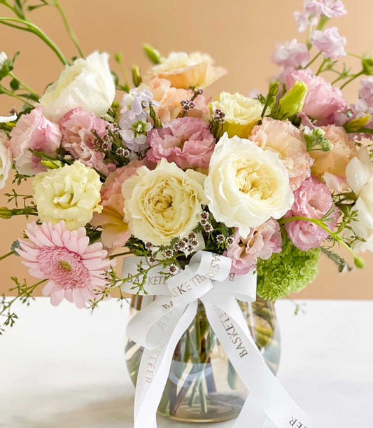 Bright pastel flower arrangement with roses, lisianthus, and gerbera in clear glass vase