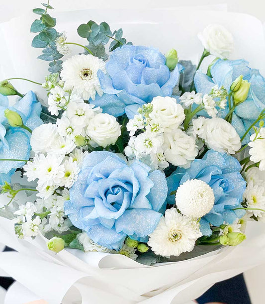 Blue roses and white blooms fresh birthday bouquet with eucalyptus, wrapped in white paper