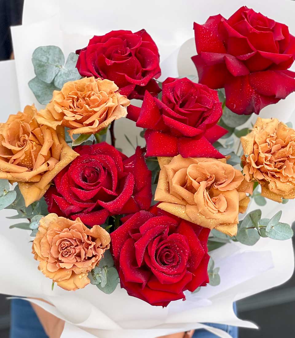 Romantic deep red and gold rose bouquet with eucalyptus, fresh Ecuador blooms wrapped in white paper