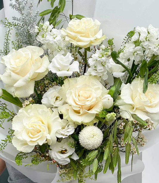 Pure white roses and lisianthus graduation bouquet with delicate stock flowers and silvery foliage