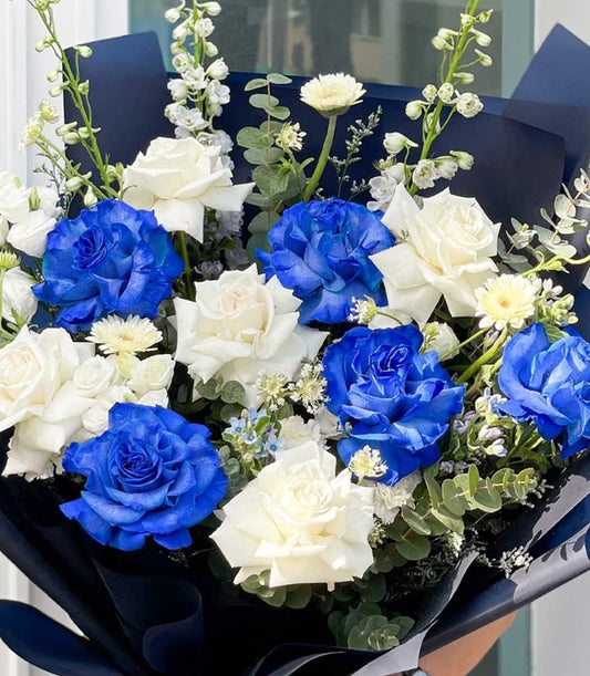 Deep blue and white roses with eucalyptus in dark wrapped bouquet for celebrations