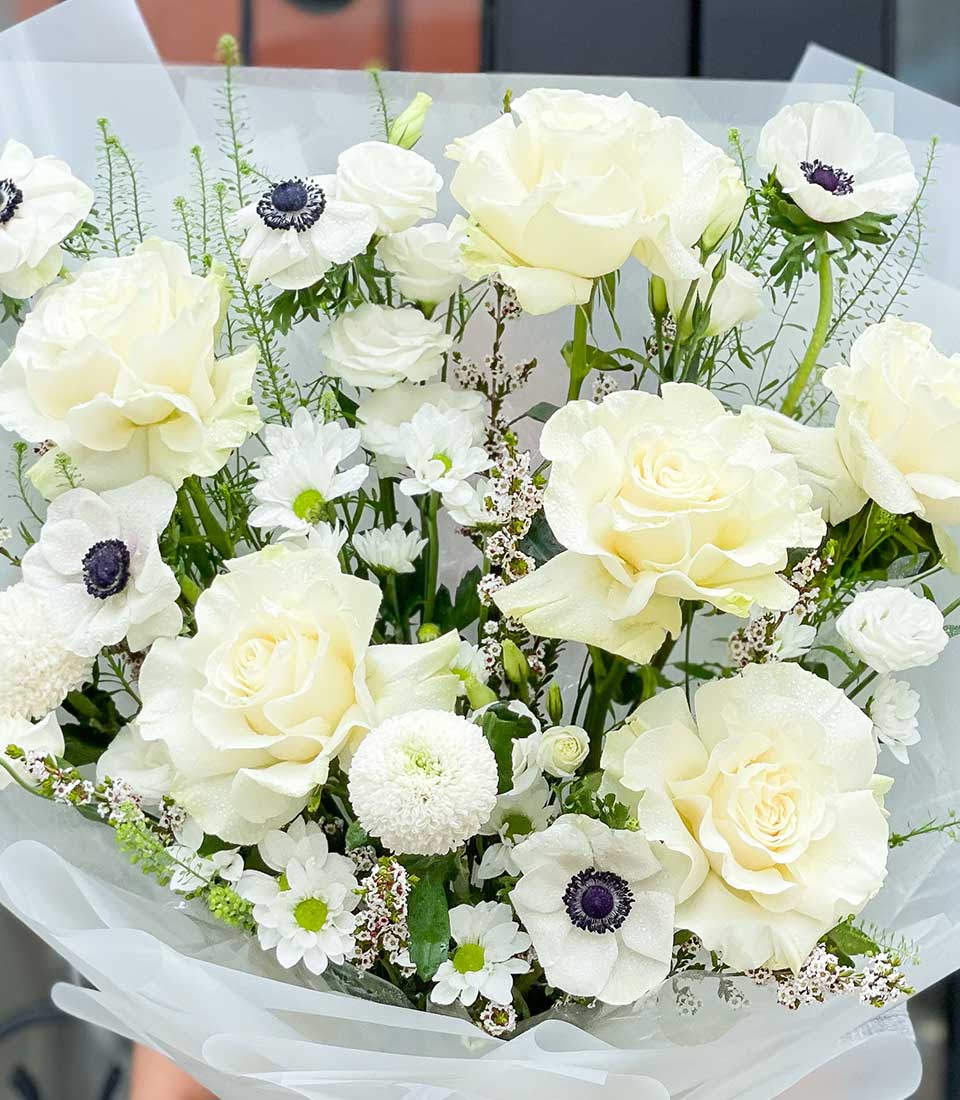White rose and anemone bouquet for graduation, wrapped in translucent paper