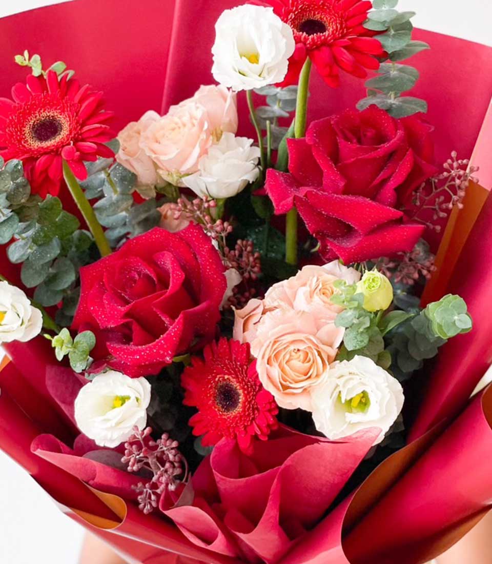 Vibrant red and pink roses with gerbera daisies and white eustoma wrapped in deep red paper, fresh graduation flowers gift