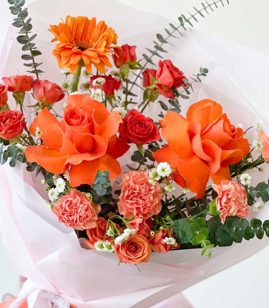 Warm amber roses and gerbera daisy graduation bouquet with pink ribbon wrap