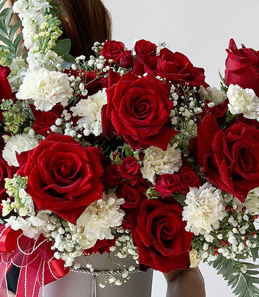 Red roses and white carnations graduation flower arrangement in grey hatbox with ribbon