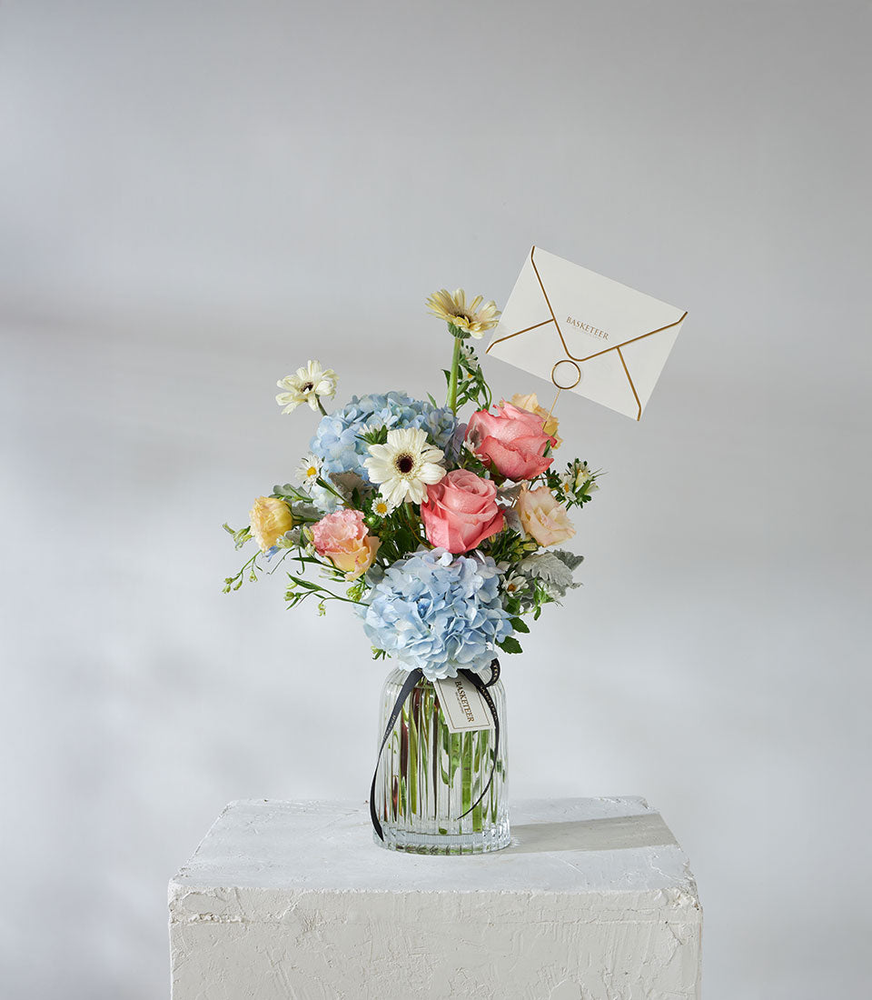 Premium Kahara roses and blue hydrangeas in clear glass vase with black ribbon