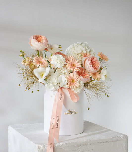 Juliet English garden roses, hydrangeas, and peach gerberas in white cylindrical vase with dried grasses