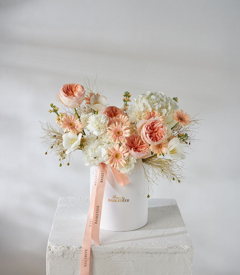Juliet English Garden roses and peach pastel flowers in white cylinder vase with ribbon
