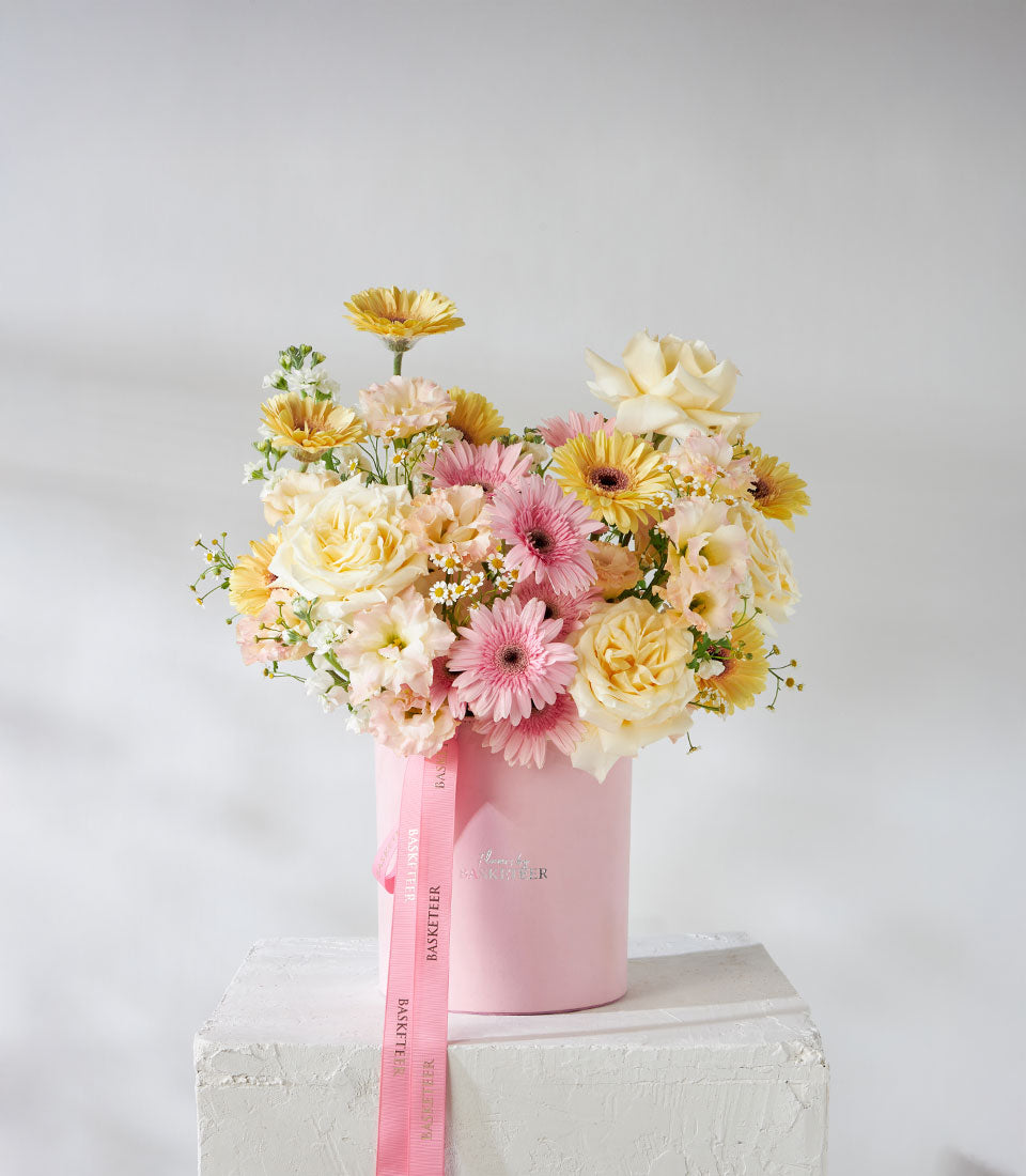 Pink velvet box with yellow, cream, and pink roses and gerbera daisies, premium fresh flower arrangement