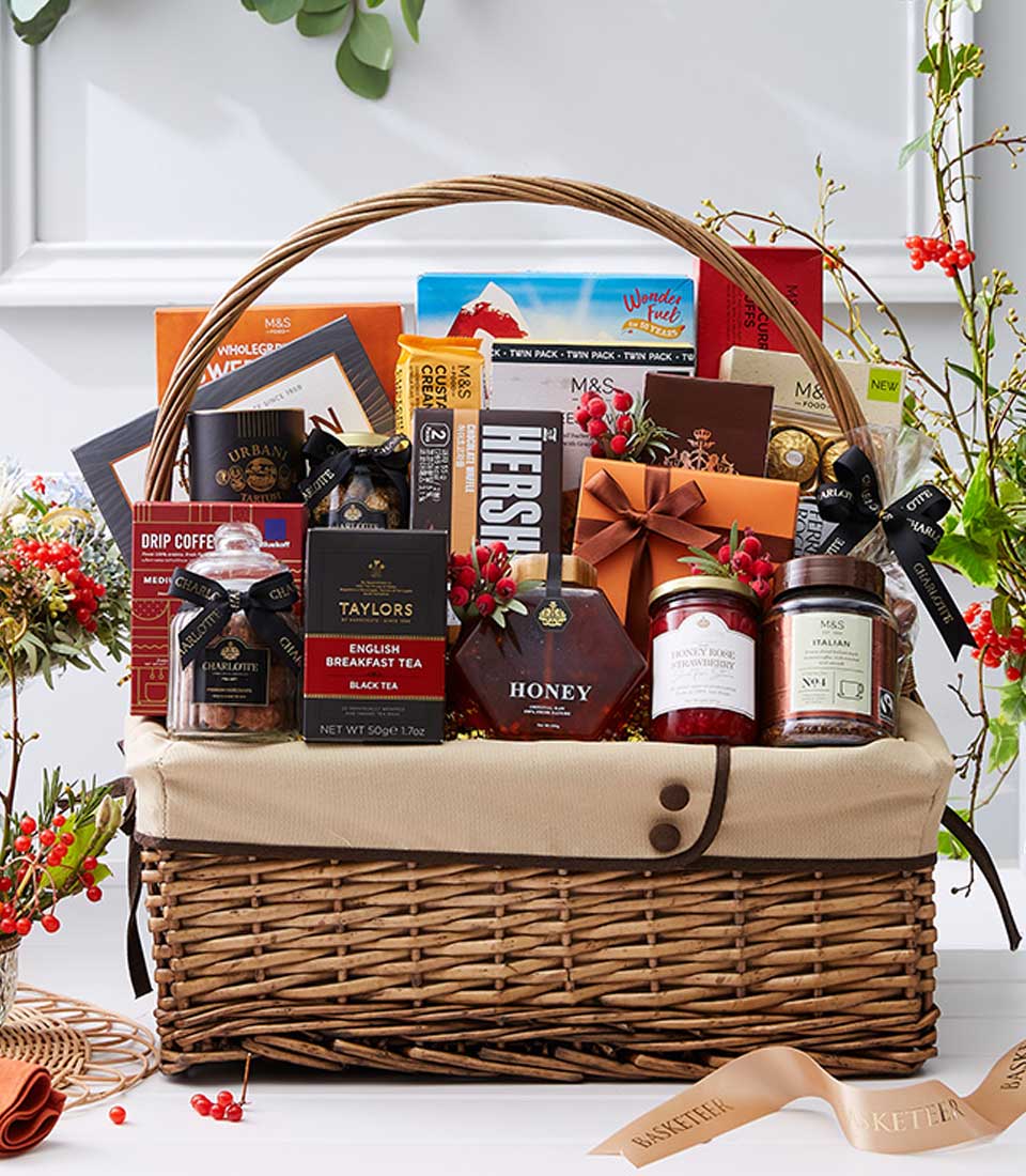 Woven wicker gift hamper filled with gourmet tea, coffee, chocolate, and honey for New Year celebrations