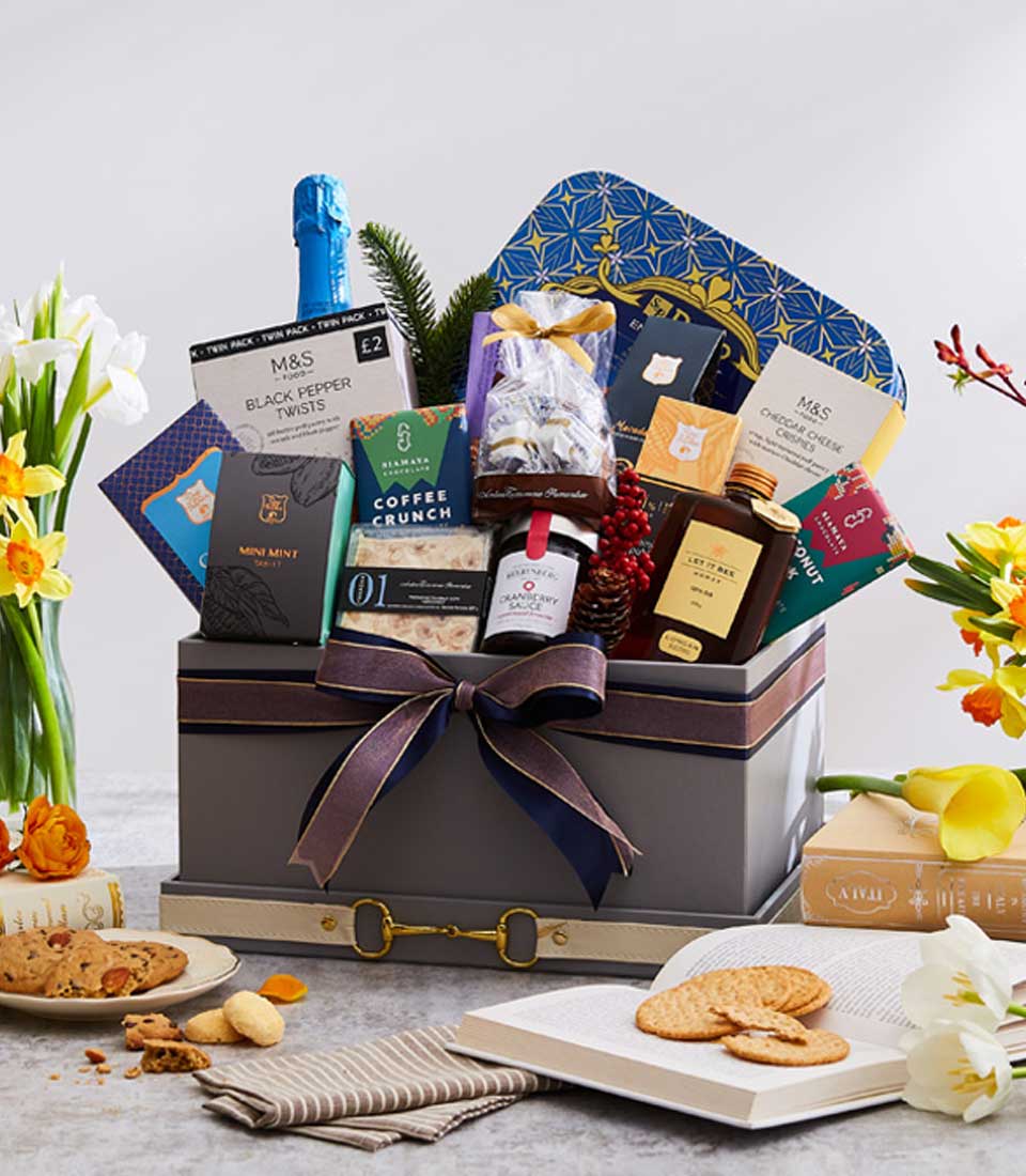 Luxe grey gift hamper with gourmet treats, sparkling wine, and gold hardware tied with navy ribbon