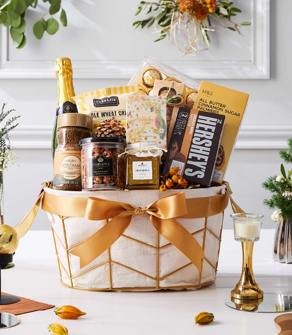 Luxury gold-trimmed wire basket with sparkling wine, gourmet coffee, chocolates, and artisan sweets for New Year gifting