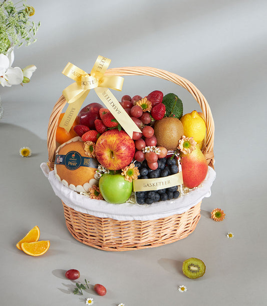 Woven wicker fruit gift basket with imported apples, grapes, berries, and citrus, tied with yellow ribbon