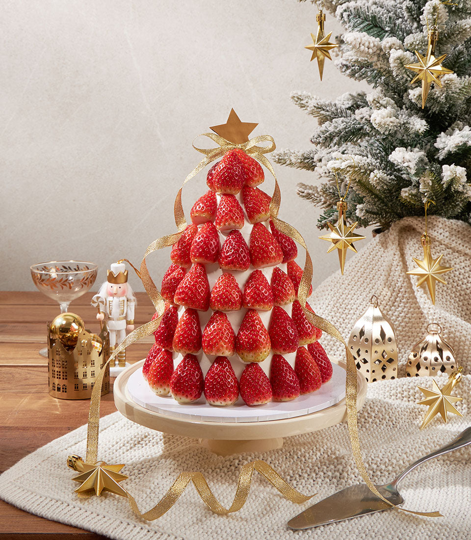 Festive strawberry sponge Christmas tree cake with fresh berries, white frosting, and gold star topper by Charlotte Bakery