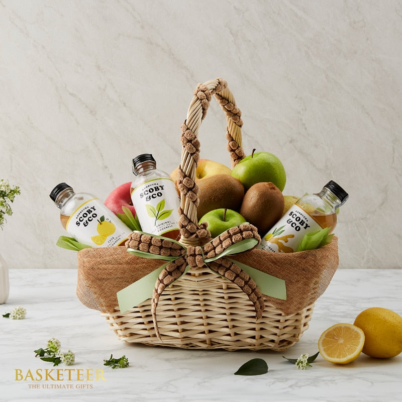 Premium mixed fruit and wellness drink gift basket with fresh apples, kiwis, and artisan beverages in woven wicker