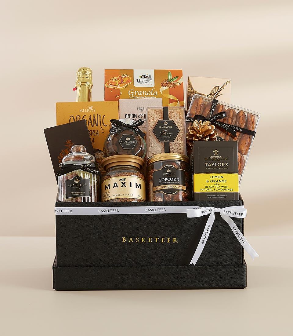 Luxury gourmet gift basket with sparkling wine, artisan biscuits, honey, and coffee in black leather box with gold ribbon