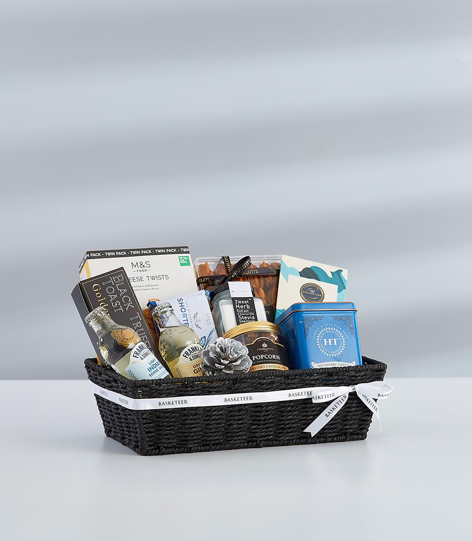 Luxury black woven gift basket with gourmet treats, truffles, and champagne for New Year celebrations