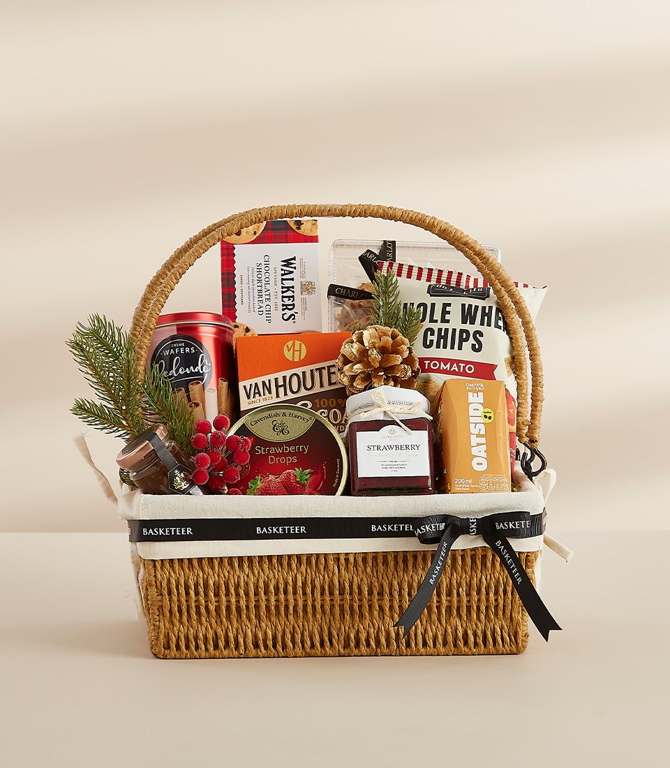 Woven brown gift basket with gourmet treats, festive greenery, and red berries for New Year gifting