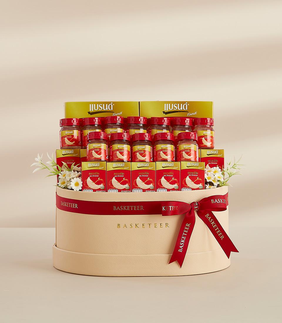 Luxury bird's nest wellness hamper with premium glass jars in cream leather basket, red ribbon, and fresh flowers