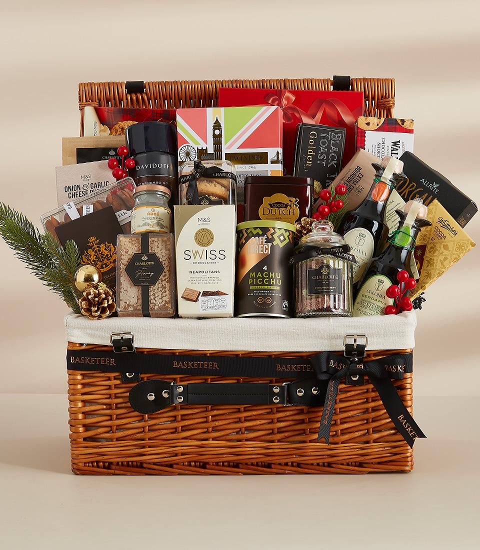 Large wicker luxury hamper filled with gourmet chocolates, preserves, coffee, and sparkling beverages with festive holiday
