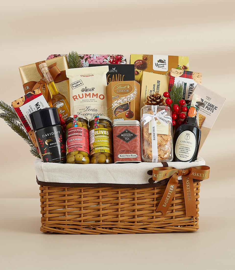 Luxury wicker gift basket filled with gourmet olive oil, pasta, chocolates, coffee, and artisan condiments with festive