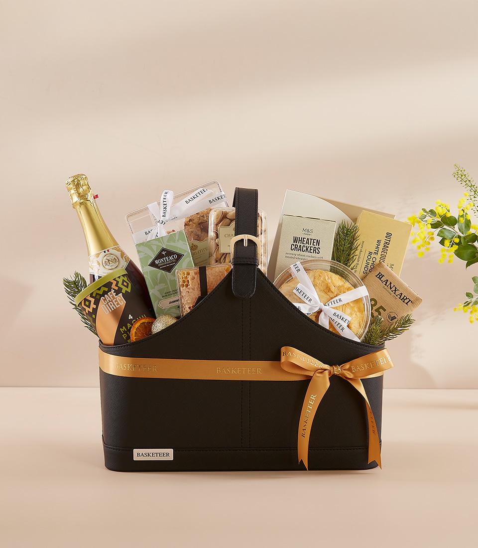 Luxury black gift basket with champagne, gourmet crackers, and artisan treats tied with gold ribbon
