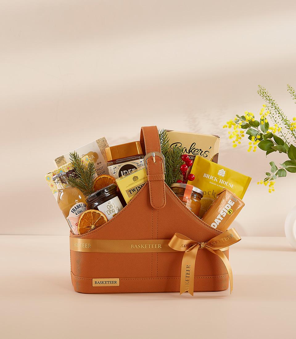 Burnt orange leather gift basket filled with gourmet essentials, sparkling juice, and artisan treats for New Year