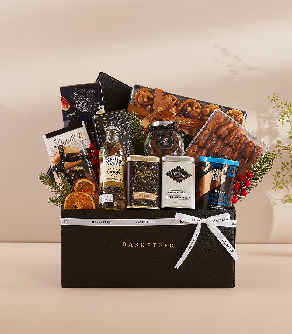 Luxury black gift hamper with gourmet treats, gold-trimmed box, festive greenery and red berries for premium holiday gifting