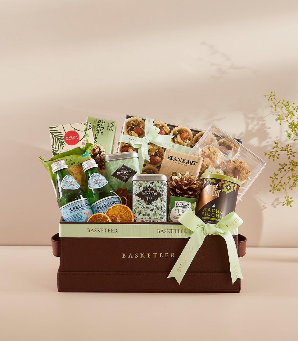Luxury New Year gift hamper with gourmet treats, sparkling water, premium tea, and artisan cookies in dark brown box with