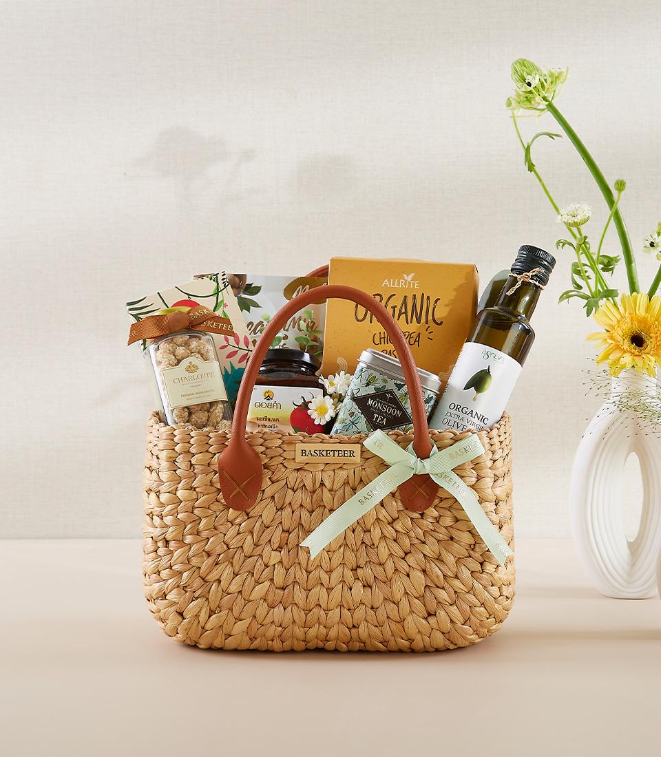 Woven straw gift basket filled with gourmet wellness treats, organic tea, olive oil, and fresh yellow flowers for New Year