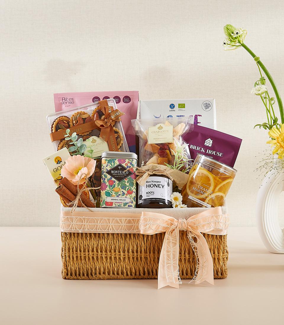 Luxury wellness gift basket with herbal tea, raw honey, marmalade, and gourmet snacks, tied with peach ribbon for New Year