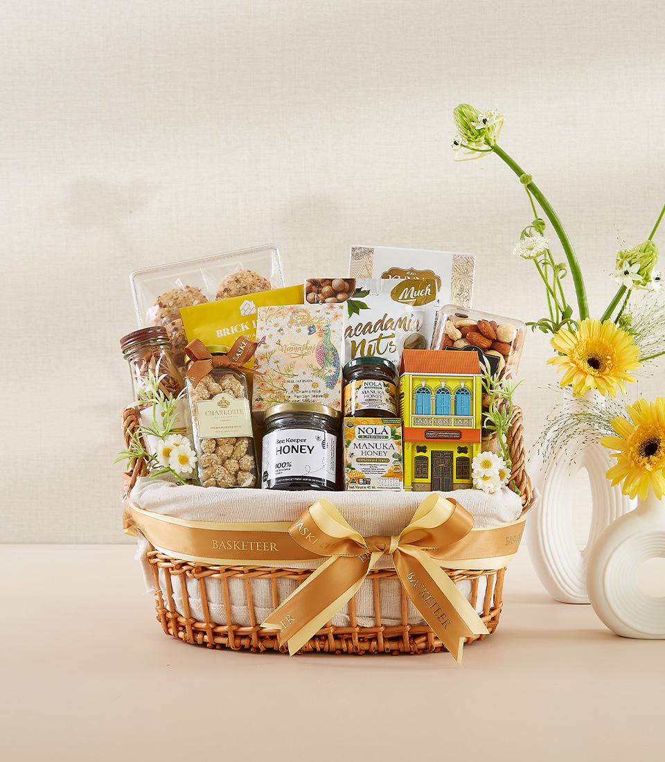 Woven wicker gourmet basket with premium honey, macadamia nuts, and artisan snacks, tied with golden ribbon