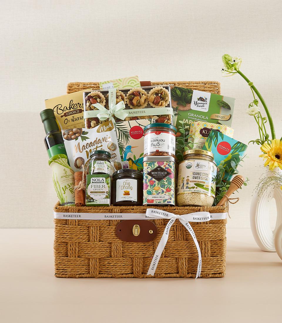Woven gourmet organic gift basket with olive oil, macadamia nuts, herbal tea, and artisan foods in glass jars