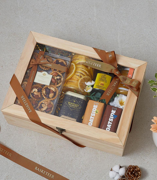 Wooden gift hamper with gourmet tarts, honey, chocolate bars and preserved lemons in clear-lid box