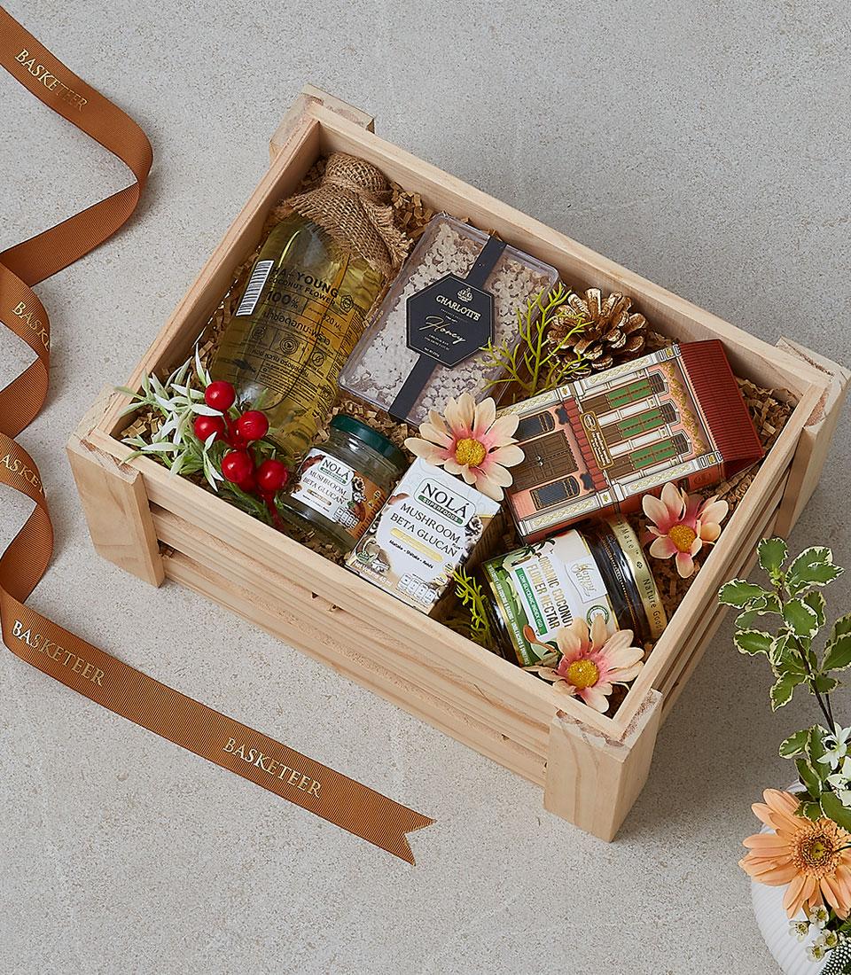 Wooden gift crate with gourmet hamper featuring honey, mushroom supplements, and artisan treats with natural styling