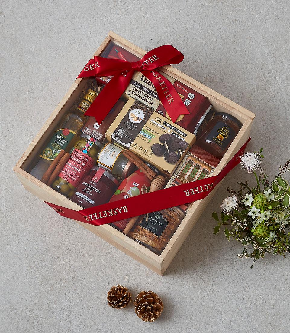 Wooden gift box filled with gourmet vinegar, olive oil, jam, honey, artisan cookies and rice crackers, tied with red ribbon