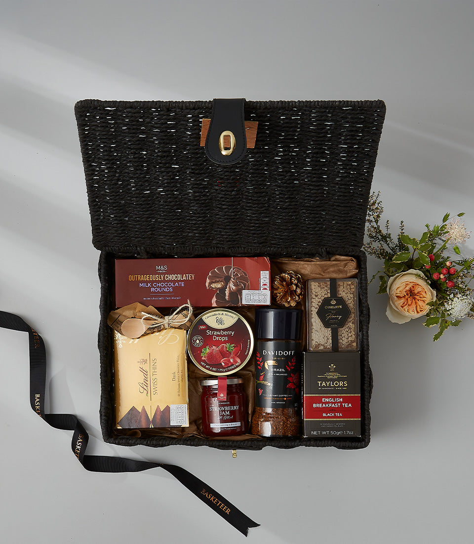 Luxury black woven hamper filled with gourmet chocolates, jam, coffee, tea, and biscuits for New Year gifting
