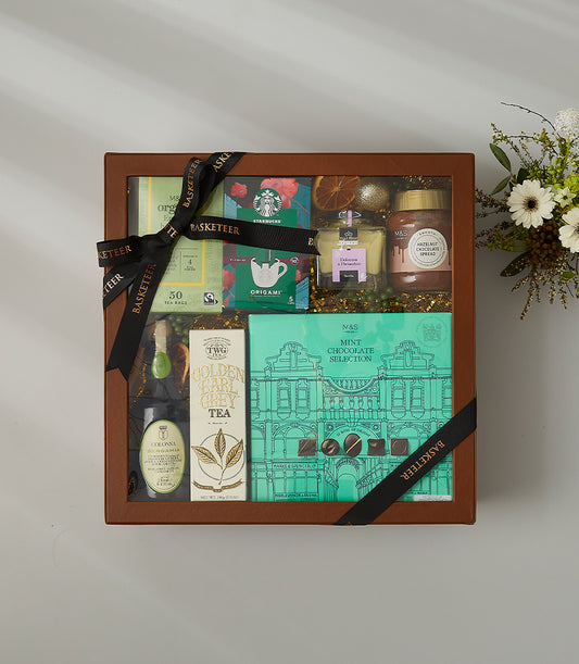 Luxury gift hamper with gourmet tea, mint chocolate, hazelnut spread, and olive oil in wooden-frame box