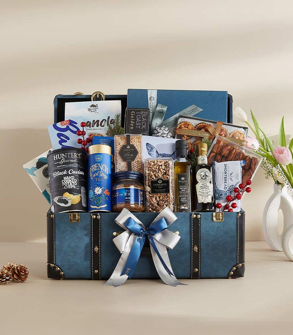 Luxury blue faux-leather hamper trunk filled with gourmet treats, caviar crisps, French tea, honey, and artisan snacks for