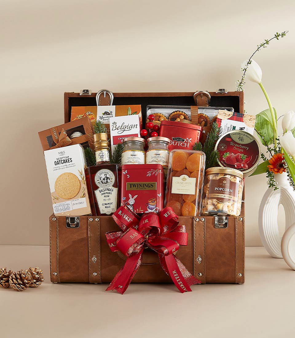 Luxury gourmet treasure hamper in brown leather suitcase with red ribbon, filled with Scottish oatcakes, Twinings tea,