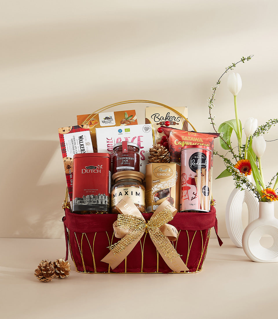 Deep red velvet gift basket with gold handle filled with gourmet treats, cocoa, jam, coffee and chocolates for New Year