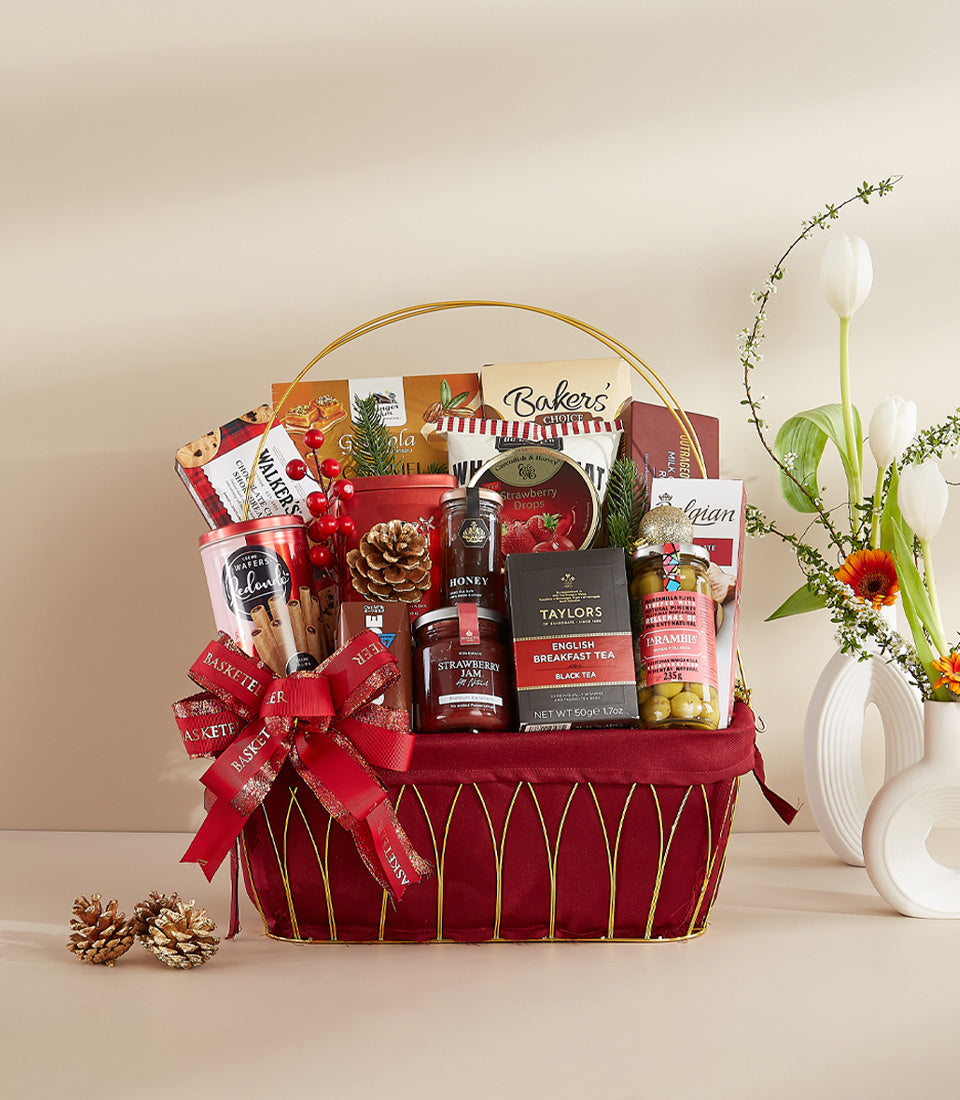 Festive red velvet gift hamper with gourmet treats, gold ribbon, and fresh flowers for New Year celebrations