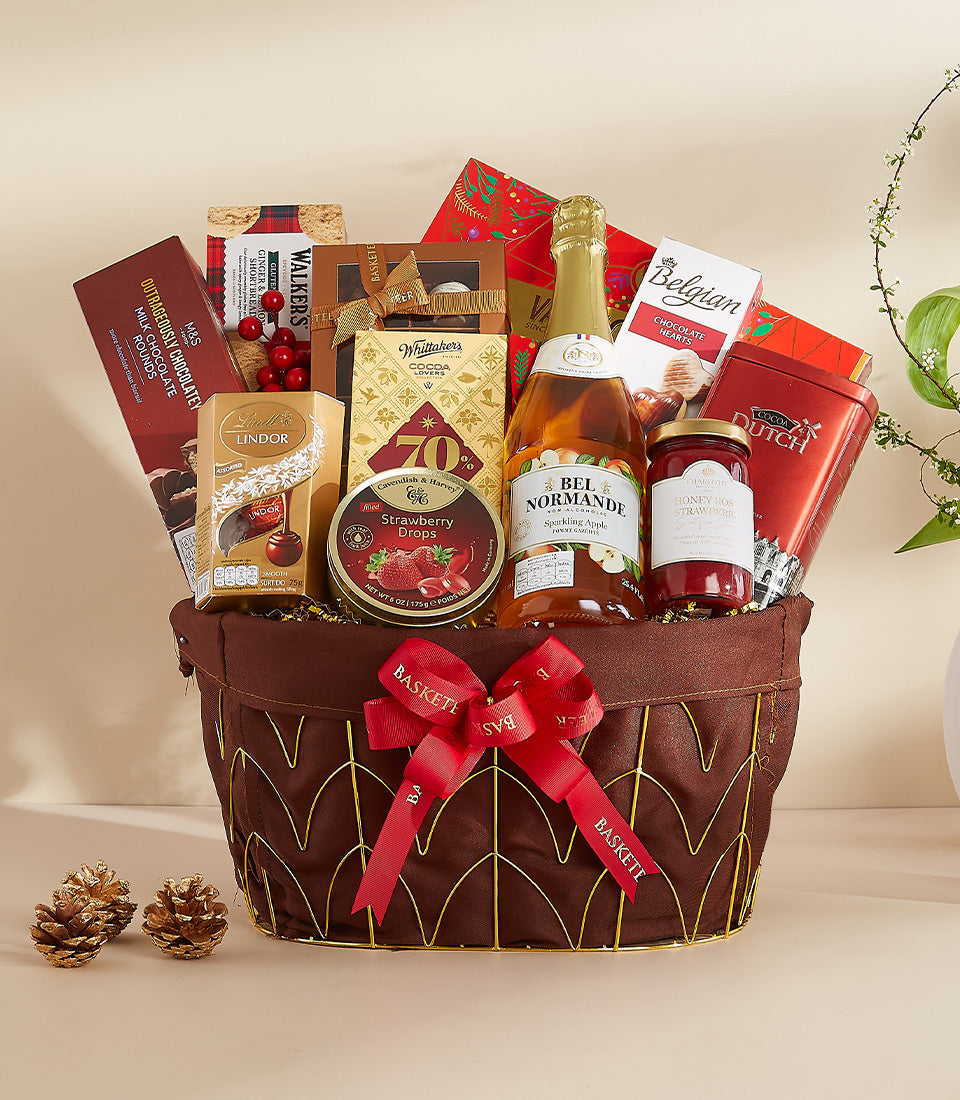 Festive gourmet gift basket with chocolate, apple cider, jam, and shortbread in gold and red packaging for New Year