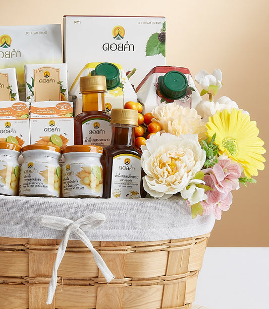 Woven wood gift basket with Doi Kham honey, preserves, and gourmet items, topped with white peonies and yellow daisies